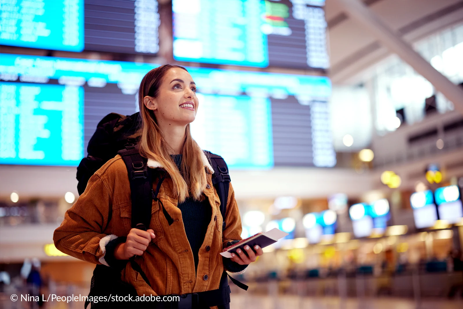 Eine Studentin steht auf einem Airport mit ihrem Pass in der Hand